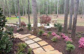 garden flagstone paver leading to a flagstone patio with an outdoor stone fireplace