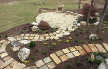 garden flagstone paver leading to a flagstone patio with an outdoor stone fireplace