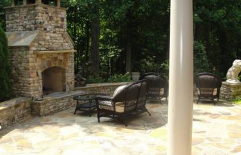 a flagstone patio with an outdoor stone fireplace