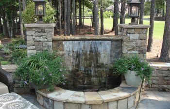 paver patio with a garden waterfall and outdoor lighting