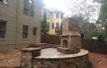 a flagstone patio with an outdoor stone fireplace