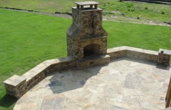 a flagstone patio with an outdoor stone fireplace