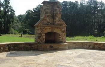 a flagstone patio with an outdoor stone fireplace