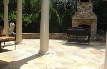 a flagstone patio with an outdoor stone fireplace