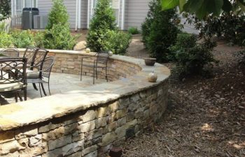 a flagstone patio with retaining walls in the backyard