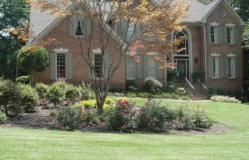 a brick house with a manicured lawn and well-cared plants